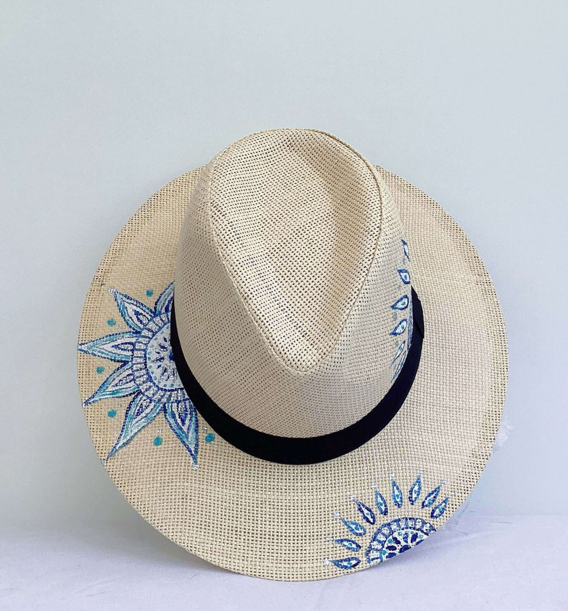 Front view of panama hat, black band at base, with hand painted blue mandalas asymmetrically positioned.