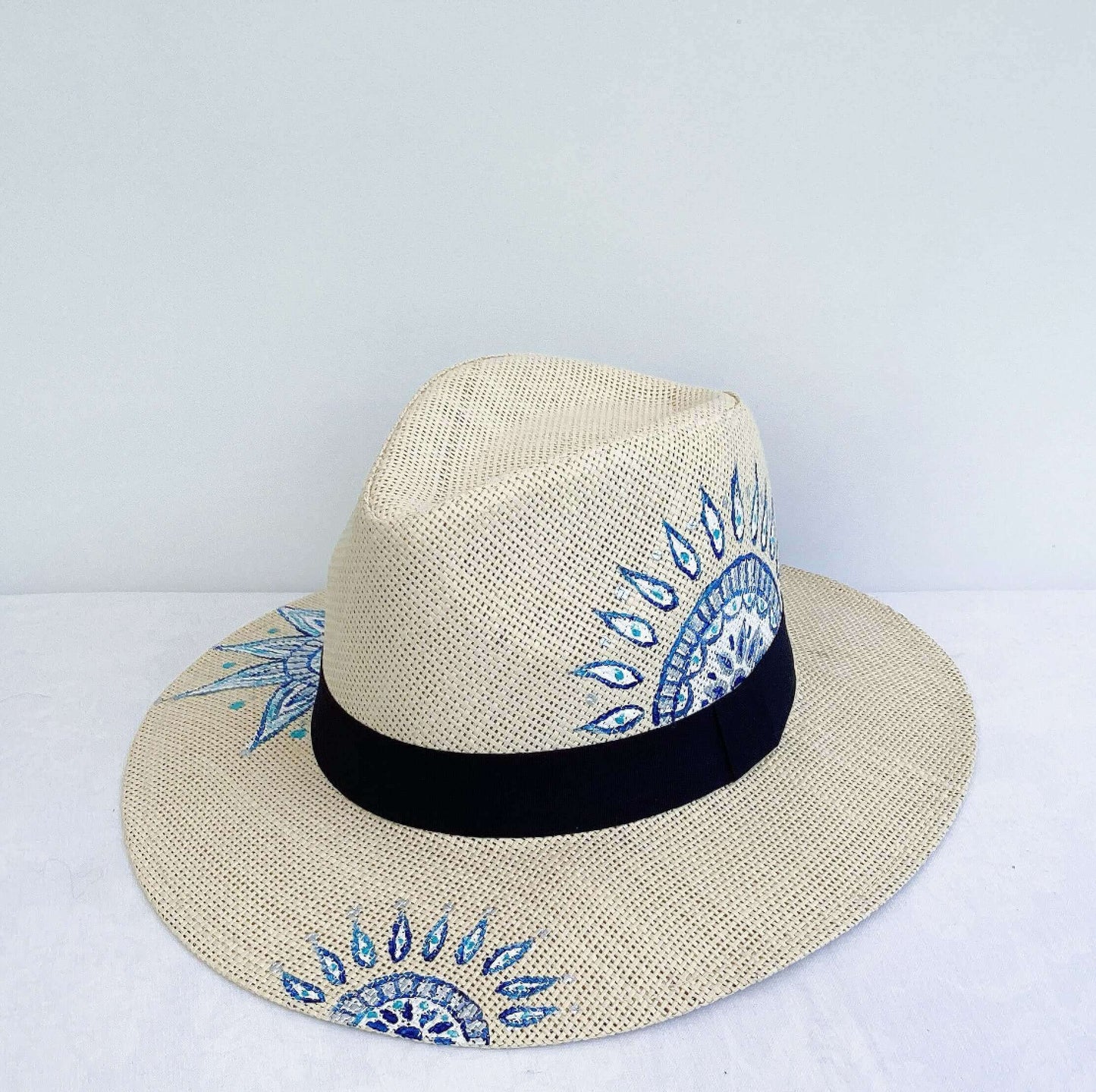 Back view of panama hat, black band at base, with hand painted blue mandalas asymmetrically positioned.