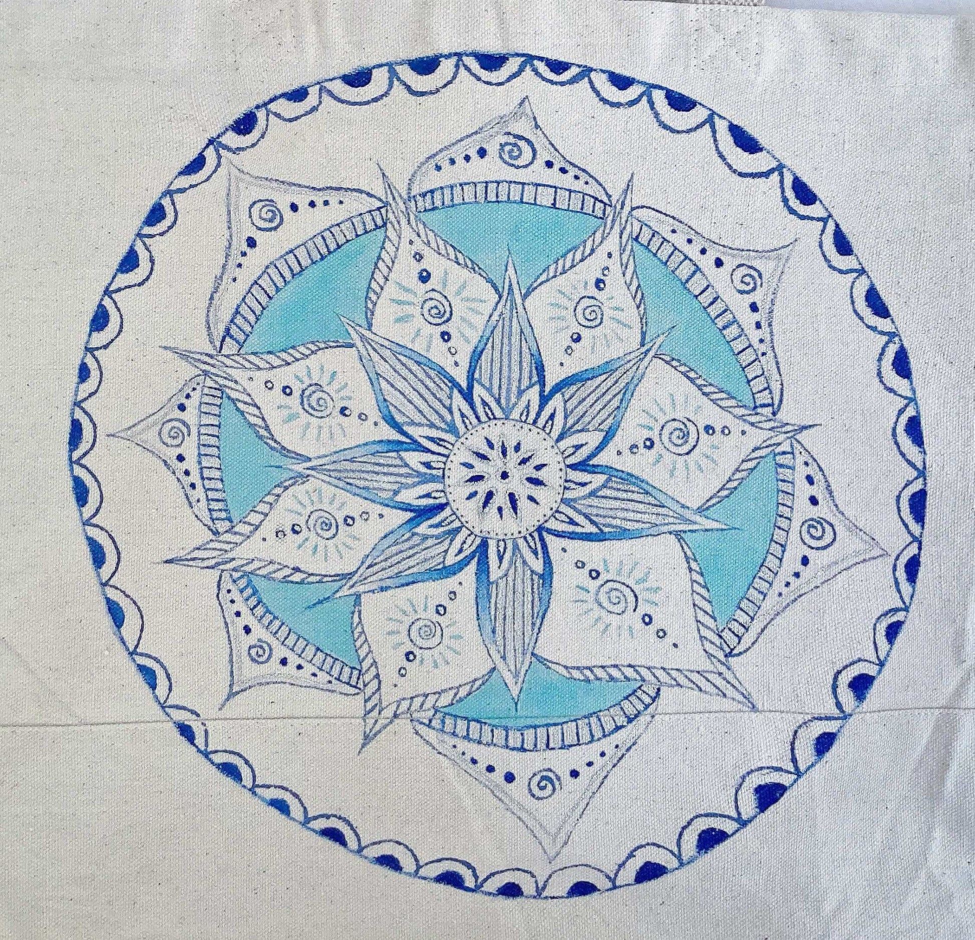 Detail view of canvas tote bag, with large hand painted blue and white mandala on the front.