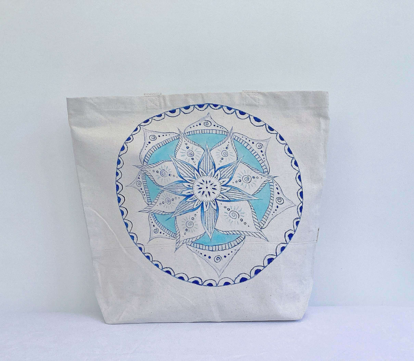 Front view of canvas tote bag, with large hand painted blue and white mandala on the front.