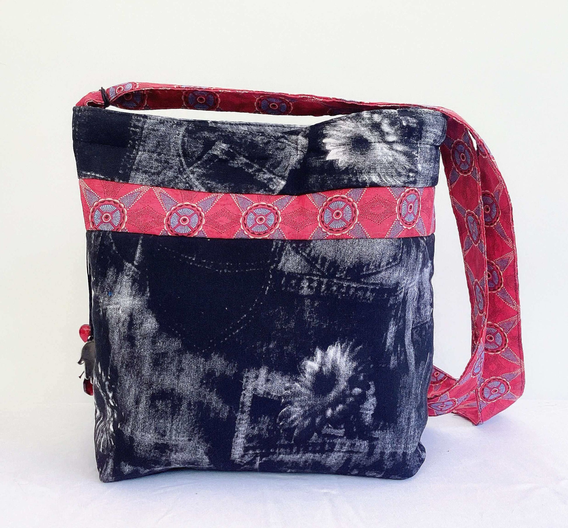 Back view of bag, black and white fabric, red shwe shwe fabric strap and band right around.