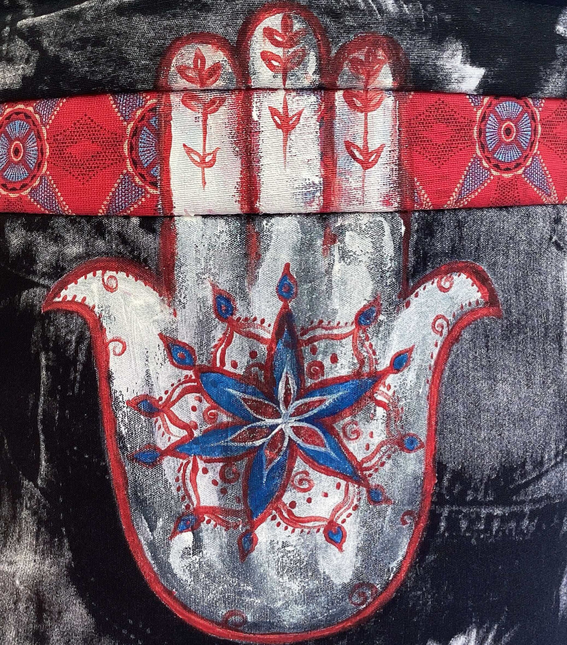 Close up of painted hamsa in white red and blue, on black and white background.