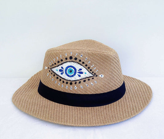 Detail view of panama hat, black band at base, hand painted blue and white evil eye asymmetrically spaced.