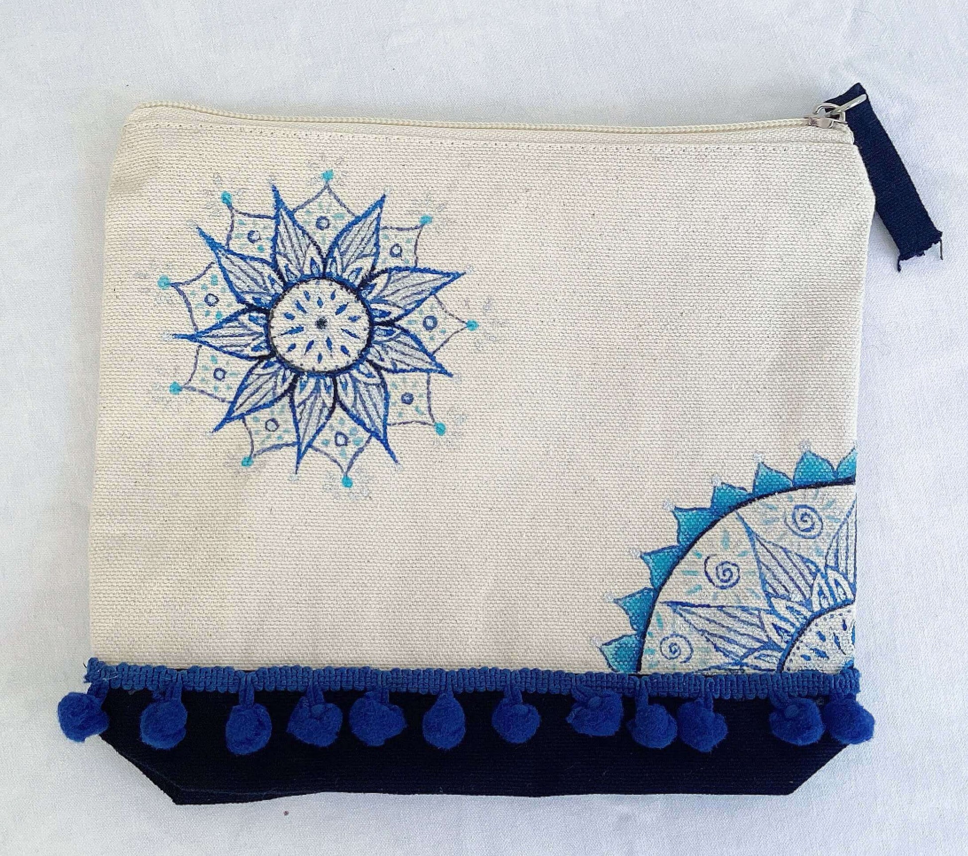 Aerial view of canvas make-up pouch, black canvas base, with hand painted blue mandalas and zip.