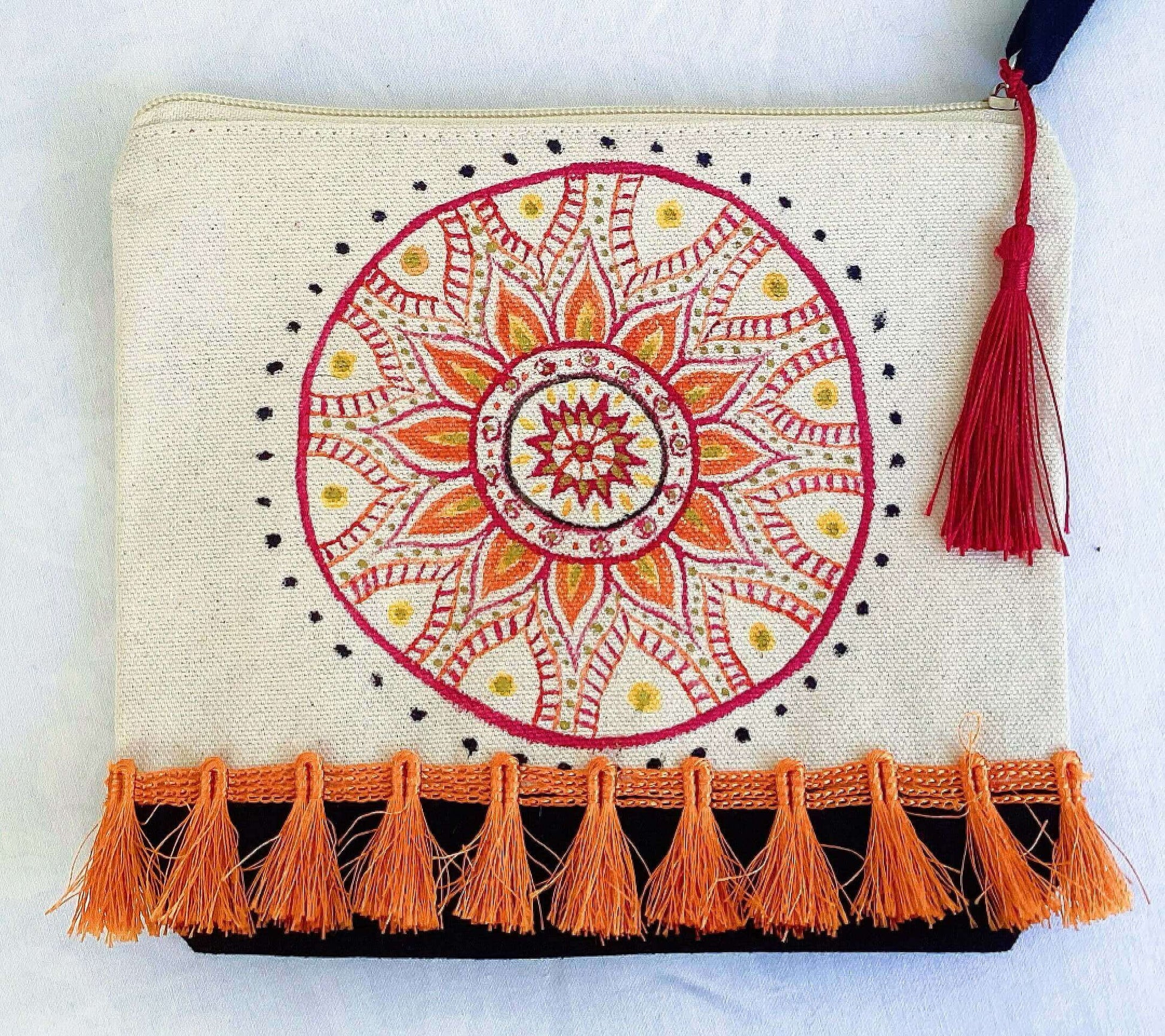 Detail of make-up pouch, black canvas base, with hand painted red and orange mandala, red tassel and zip, orange fringe.