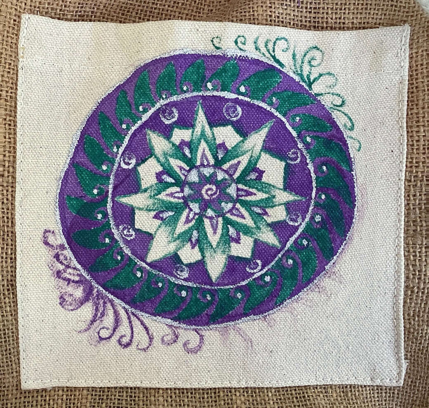 Closeup view of hessian satchel with hand painted teal and purple mandala on canvas patch.