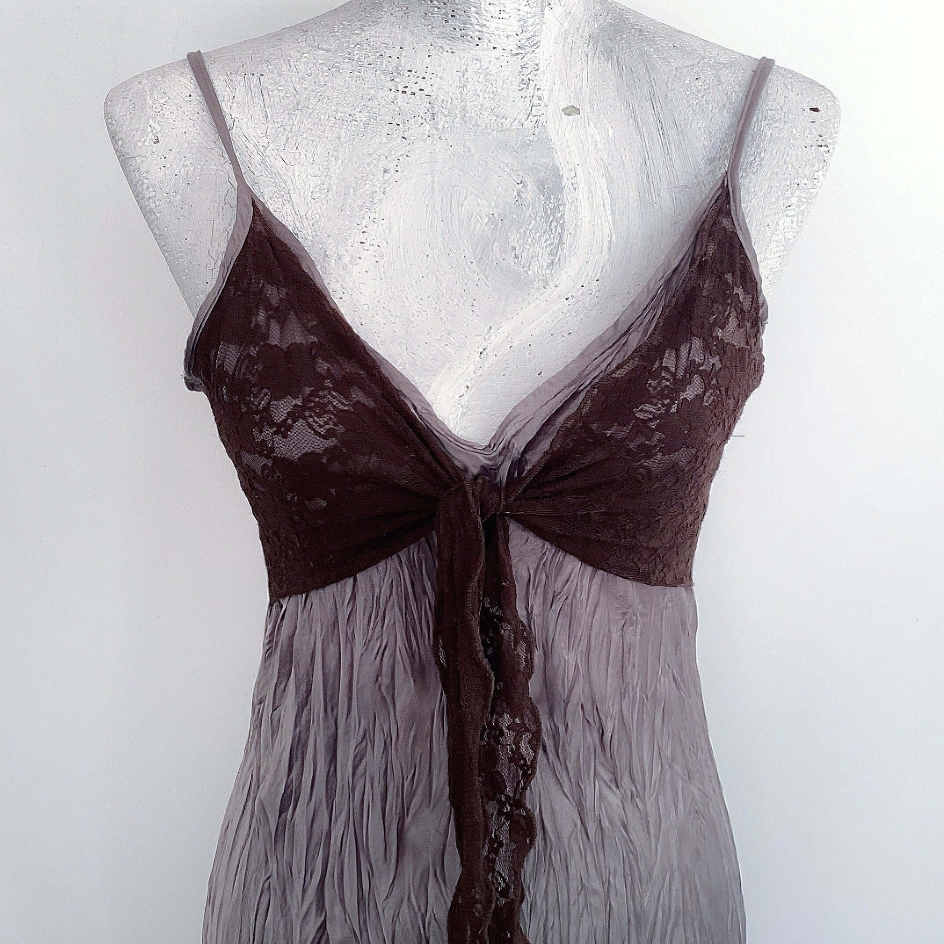 Front detail view of bodice and waist area of the dress, showing the bust ties flowing down from the center of dress.