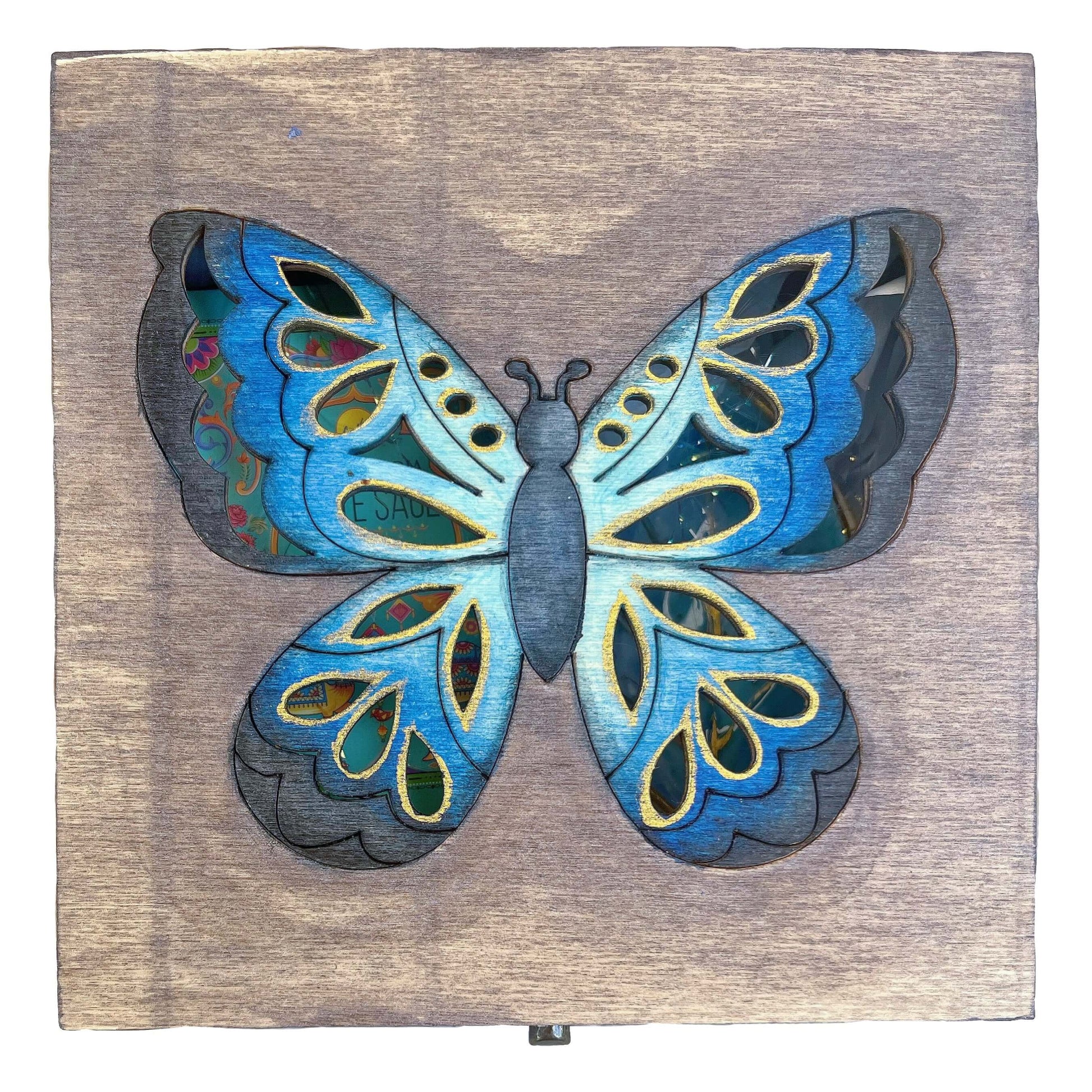 Detail view of painted lid, brown washed background, with multi blues butterfly in the center.