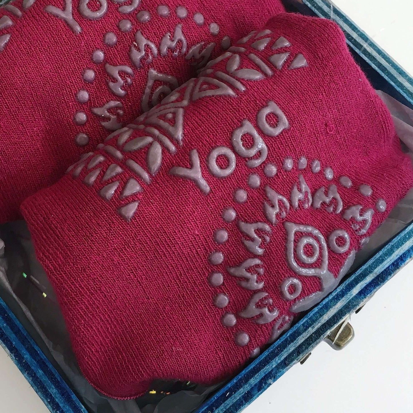 Contents detail view of plum yoga socks rolled up, exposing the non slip patterns on sole of socks.