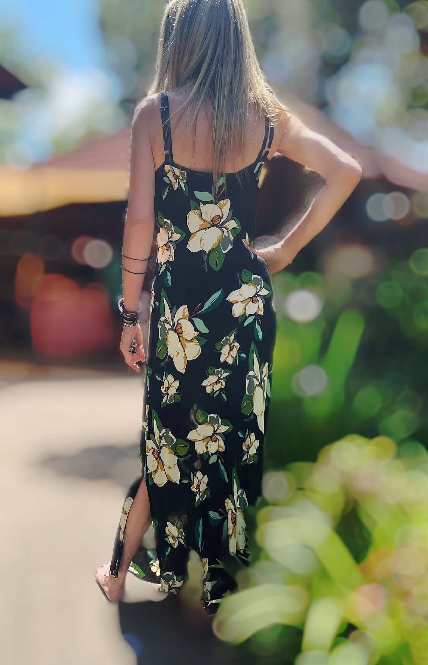 Back view of long cami dress, black viscose background with cream and green printed hibiscus flowers.