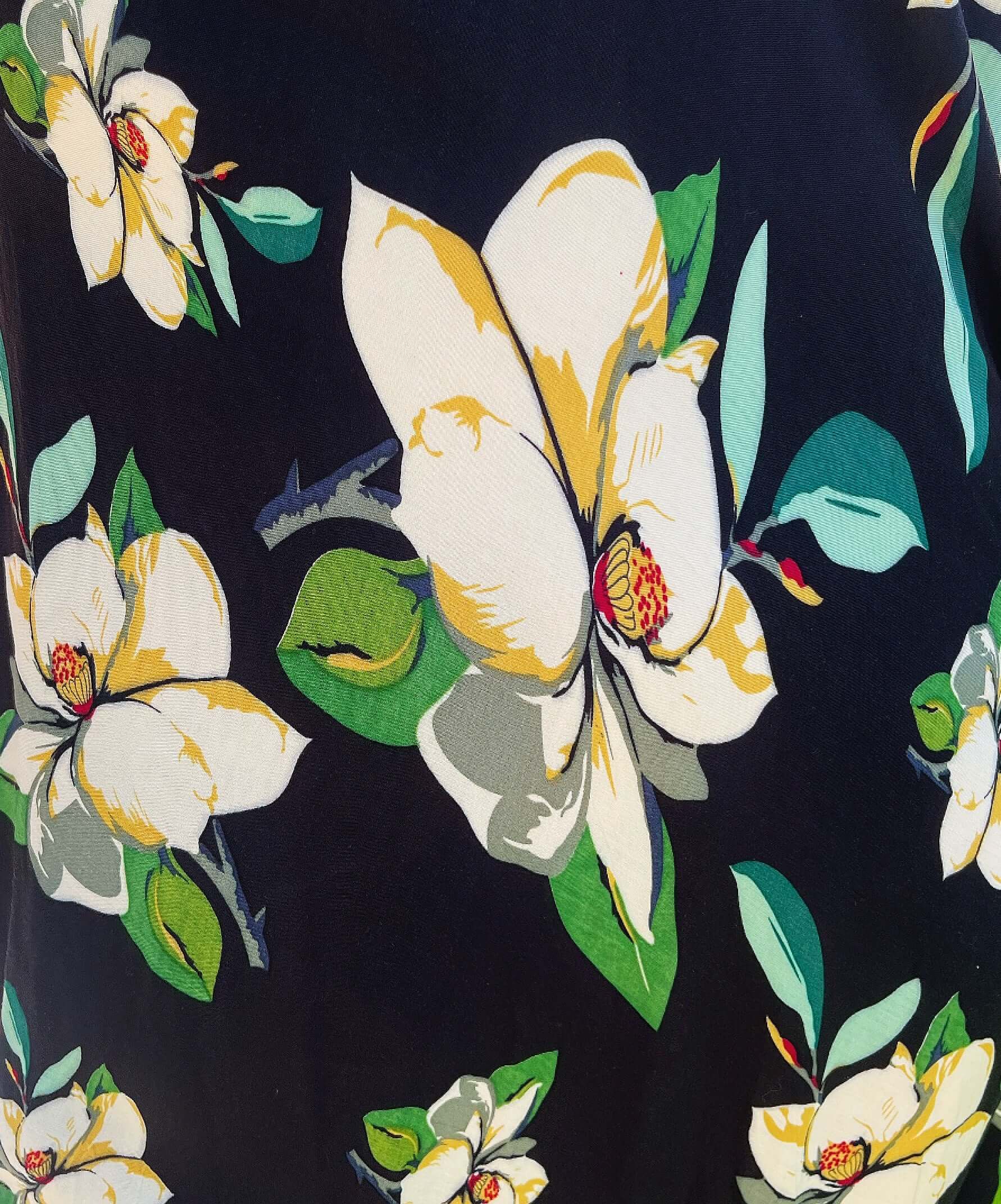 Close up view of black viscose background with cream and green printed hibiscus flowers.
