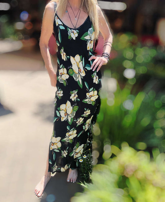 Front view of long cami dress, black viscose background with cream and green printed hibiscus flowers.