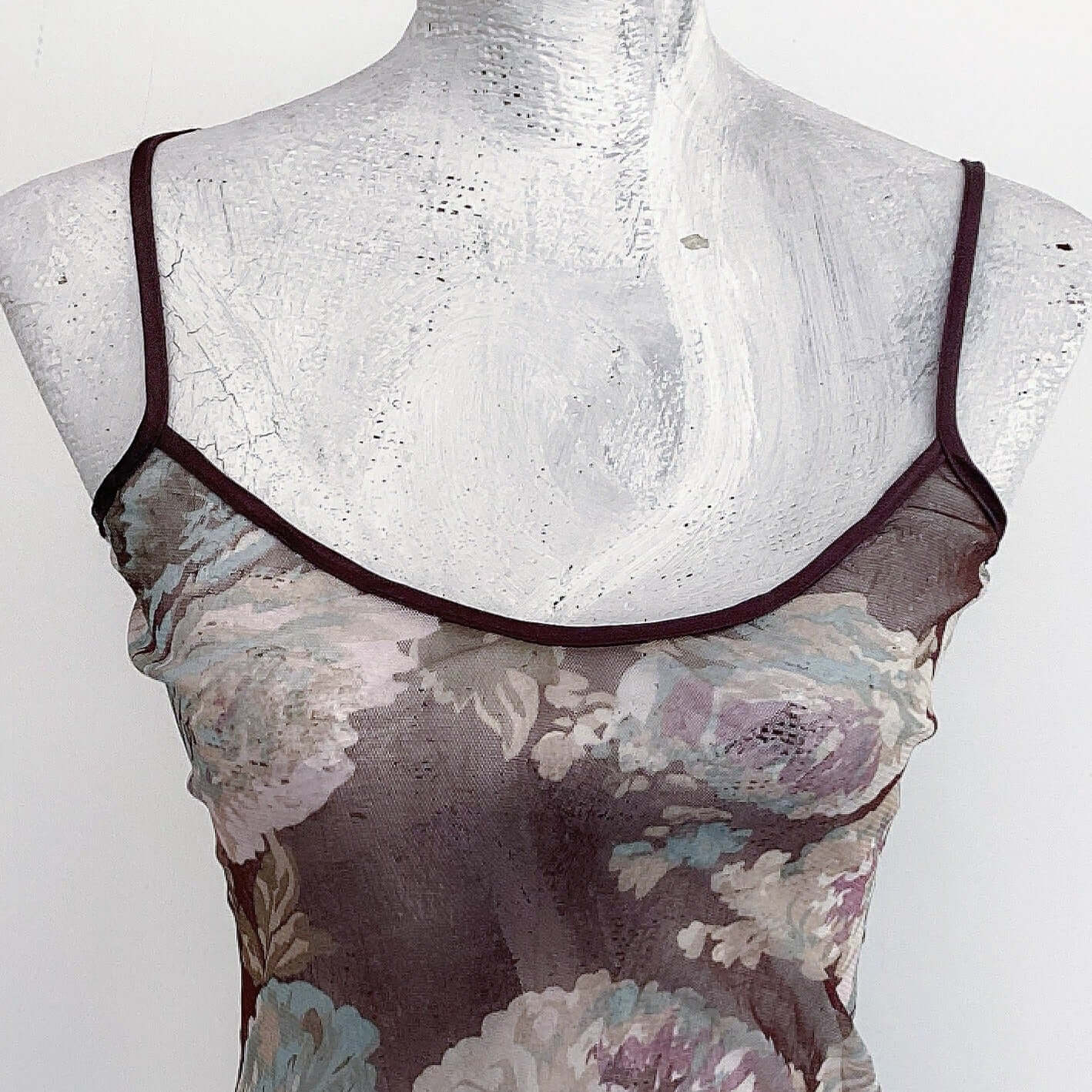 Front detail of straps and printed stretch mesh cami, brown background with large printed beige, turquoise, lilac flowers.