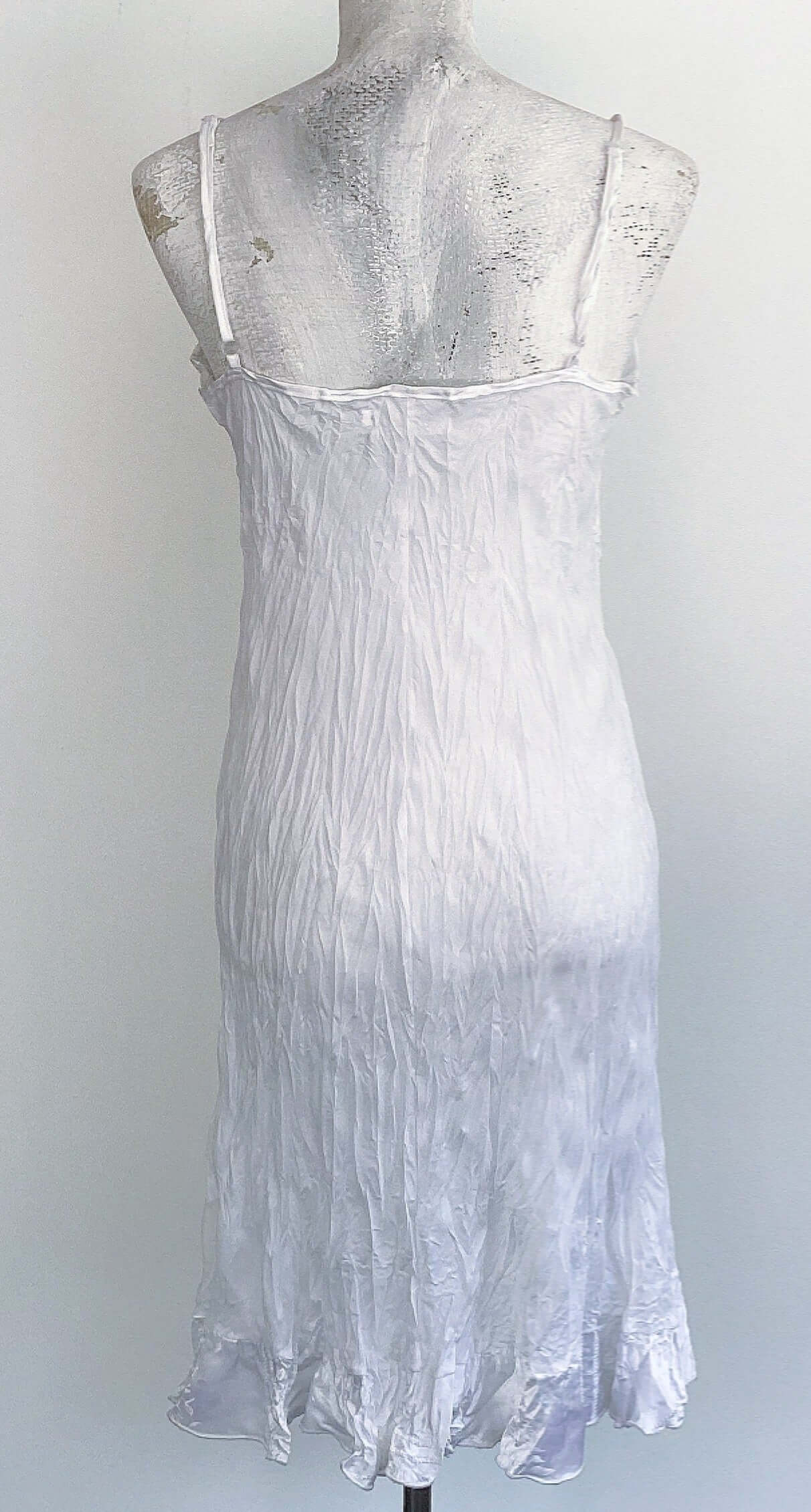 Back of white dress, which is plain white, with satin frill.