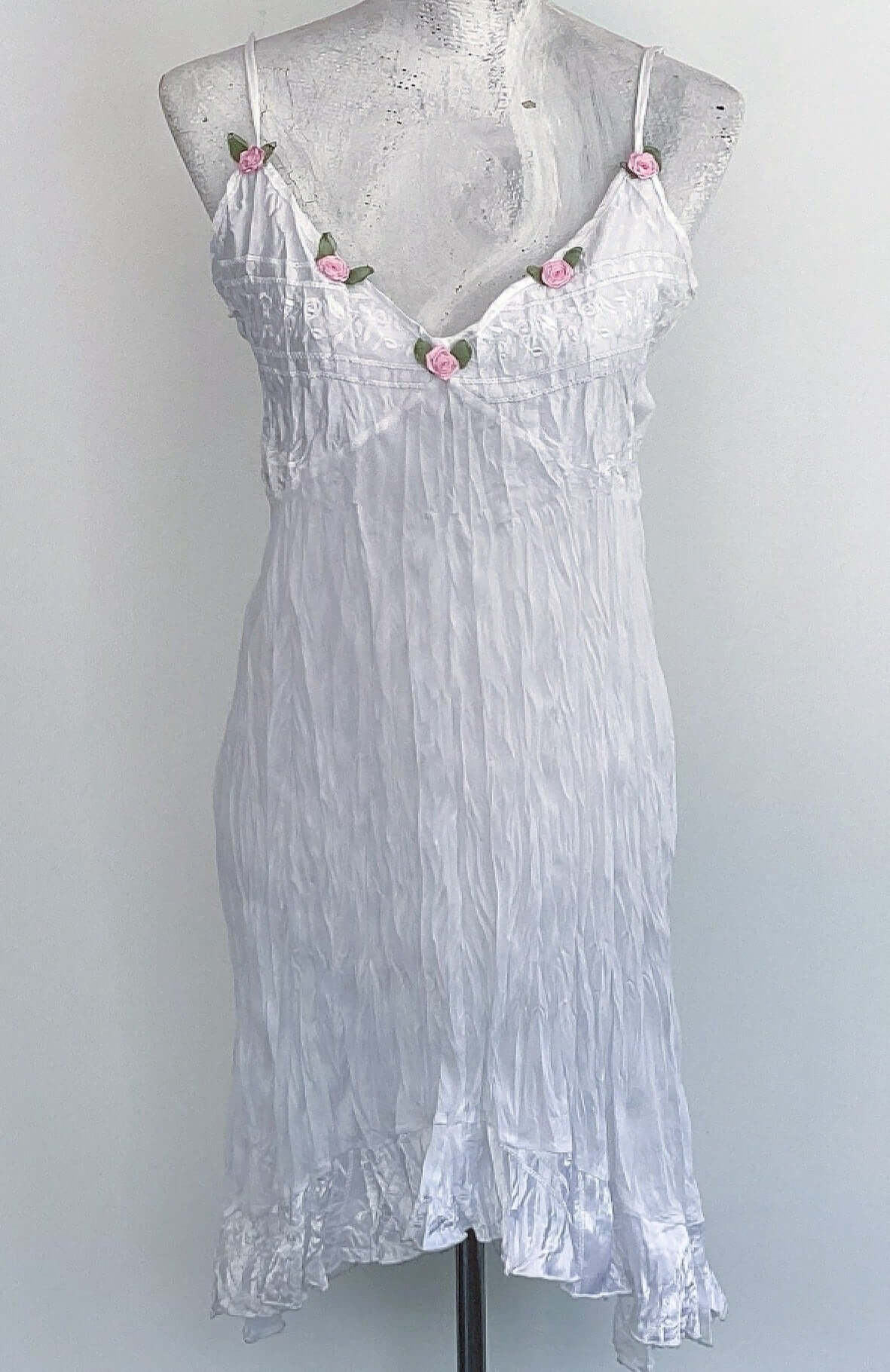 Front of white dress, with satin frill, bust and straps, and 5 pink roses with green leaves, stitched along the V neckline.