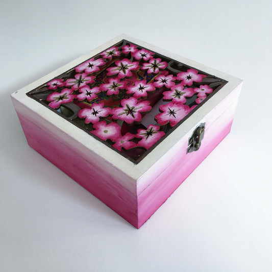 Outside view of pink painted box, fading to white and pink cherry blossom laser cut lid, with metal closing clasp.