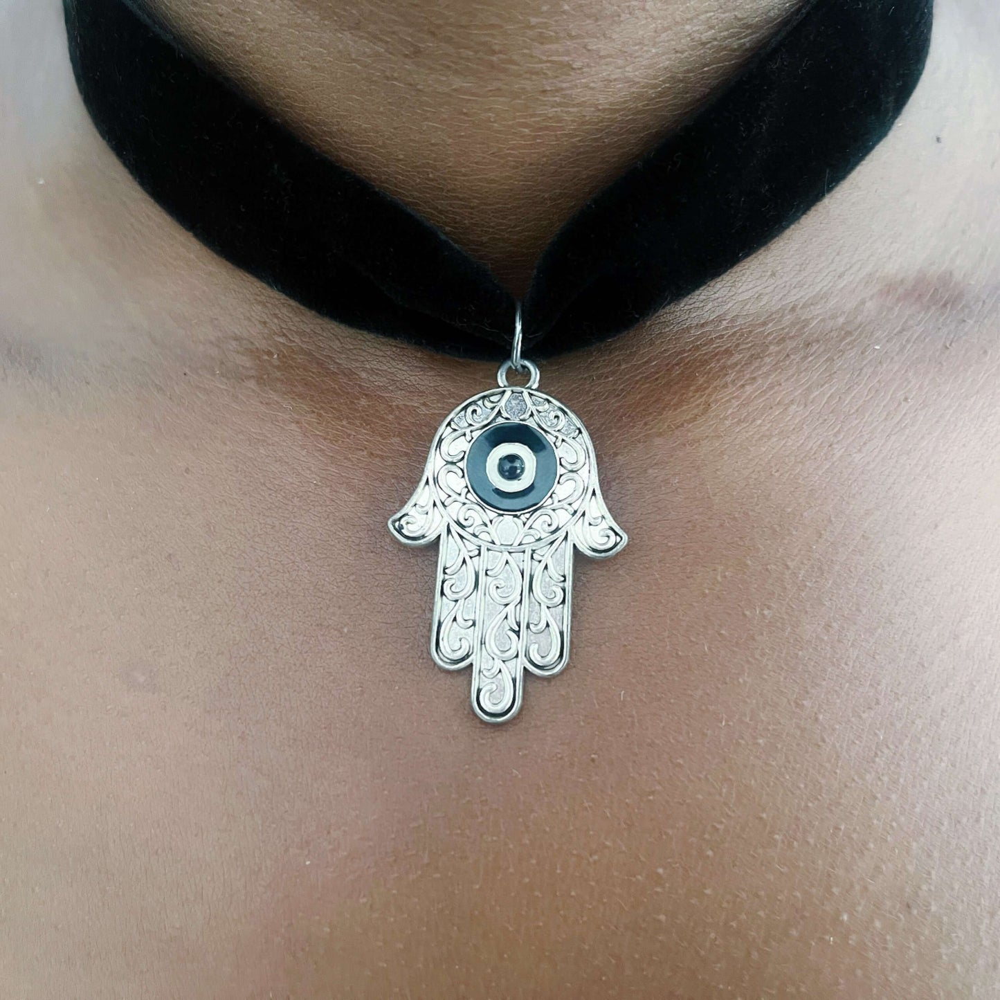 Detail view of metal hamsa on velvet black choker.