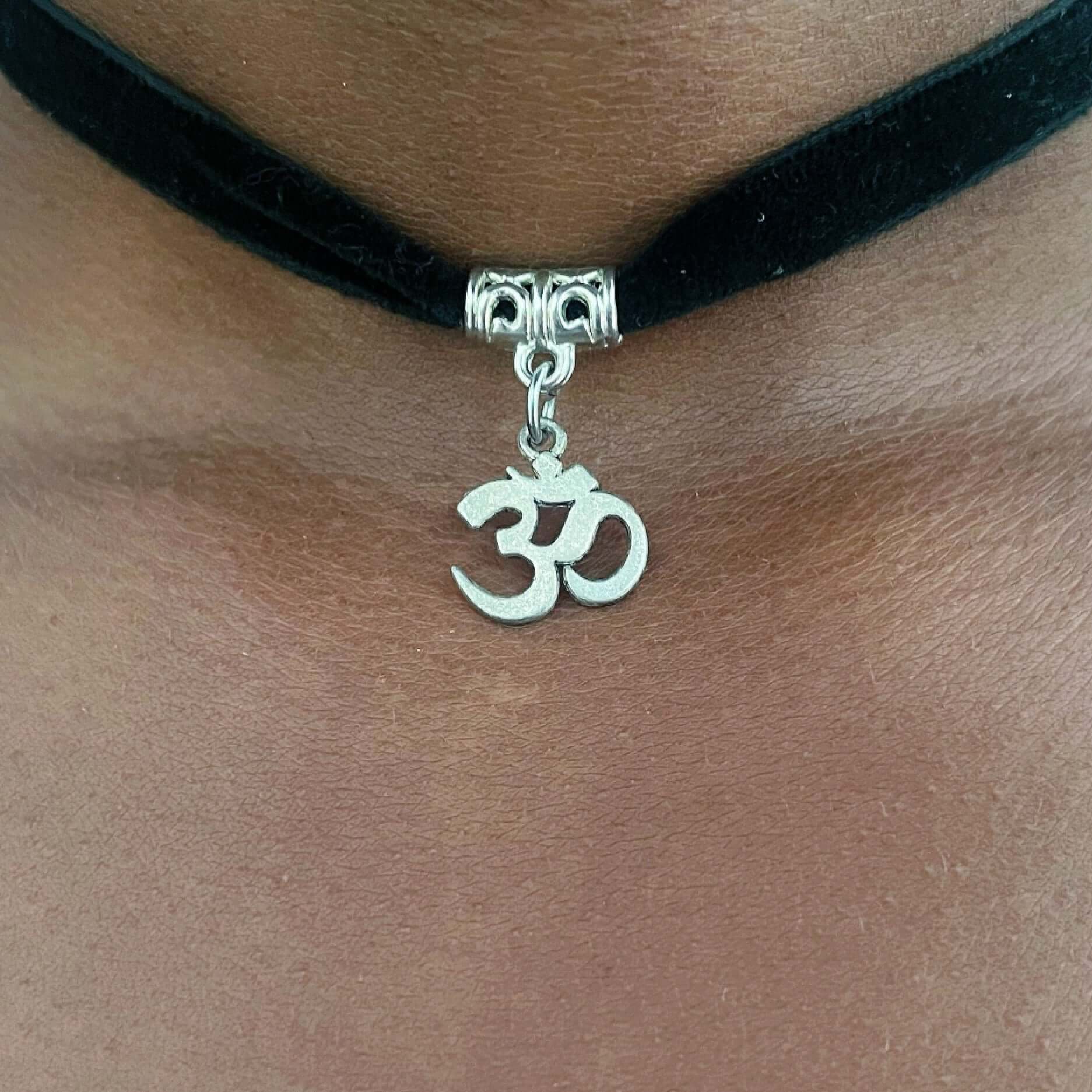 Detail view of metal om sign on velvet black choker.