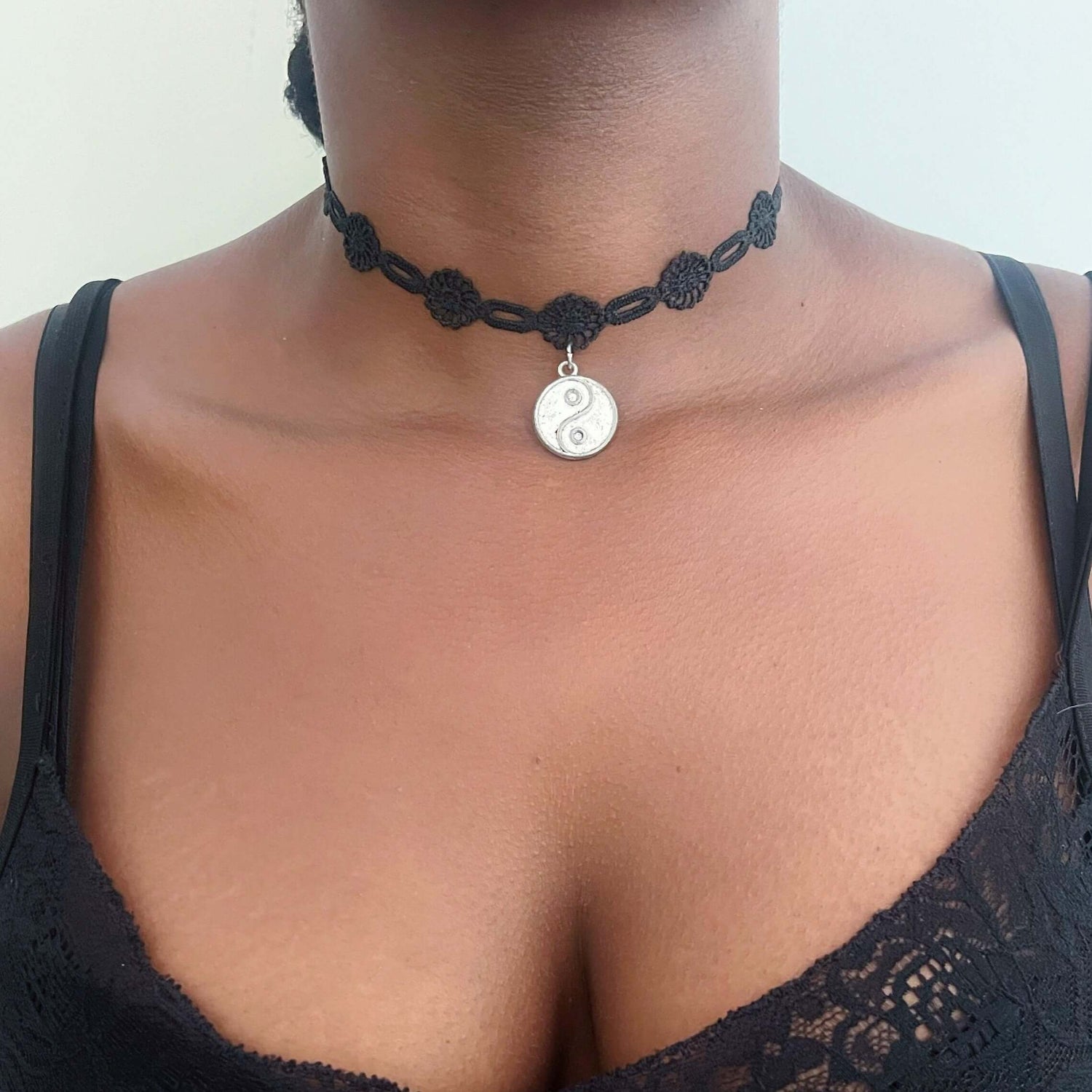 Front view of metal yin yang on embroidered black choker.