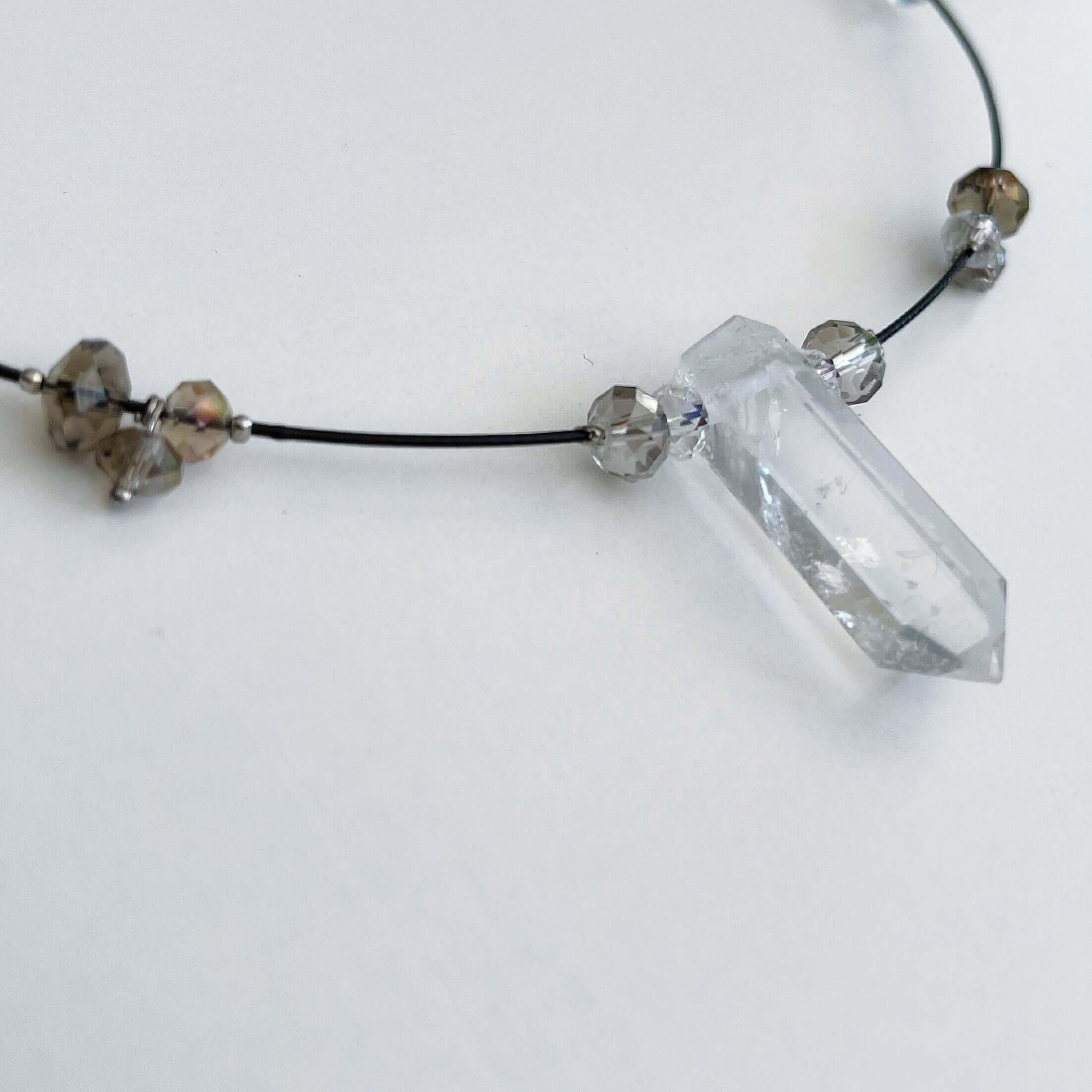 Detail view of clear quartz pendant strung onto choker with crystal beads 2cm apart all around.