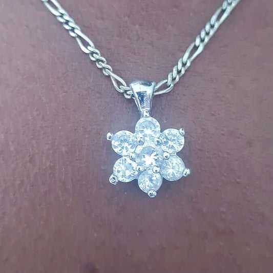 Detail view of flower shaped pendant with six cubic zirconia petals and a center on silver chain.