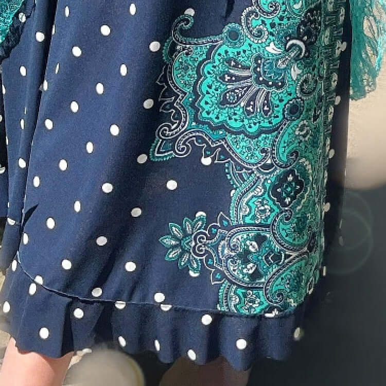 Detail of navy stretch lycra, white dots, and printed aqua design down the left hand side of dress, frill on the hem.