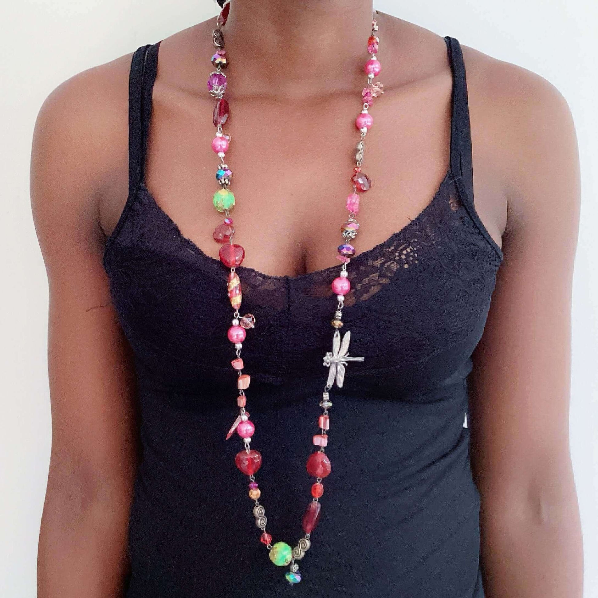 Multi colored necklace shown around the neck, with reds, greens, pinks, crystal, acrylic, pewter, and glass beads.