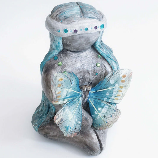 Front of elemental, brown wash painted figure, jewel band on head, bluish long hair, holding a feather butterfly.
