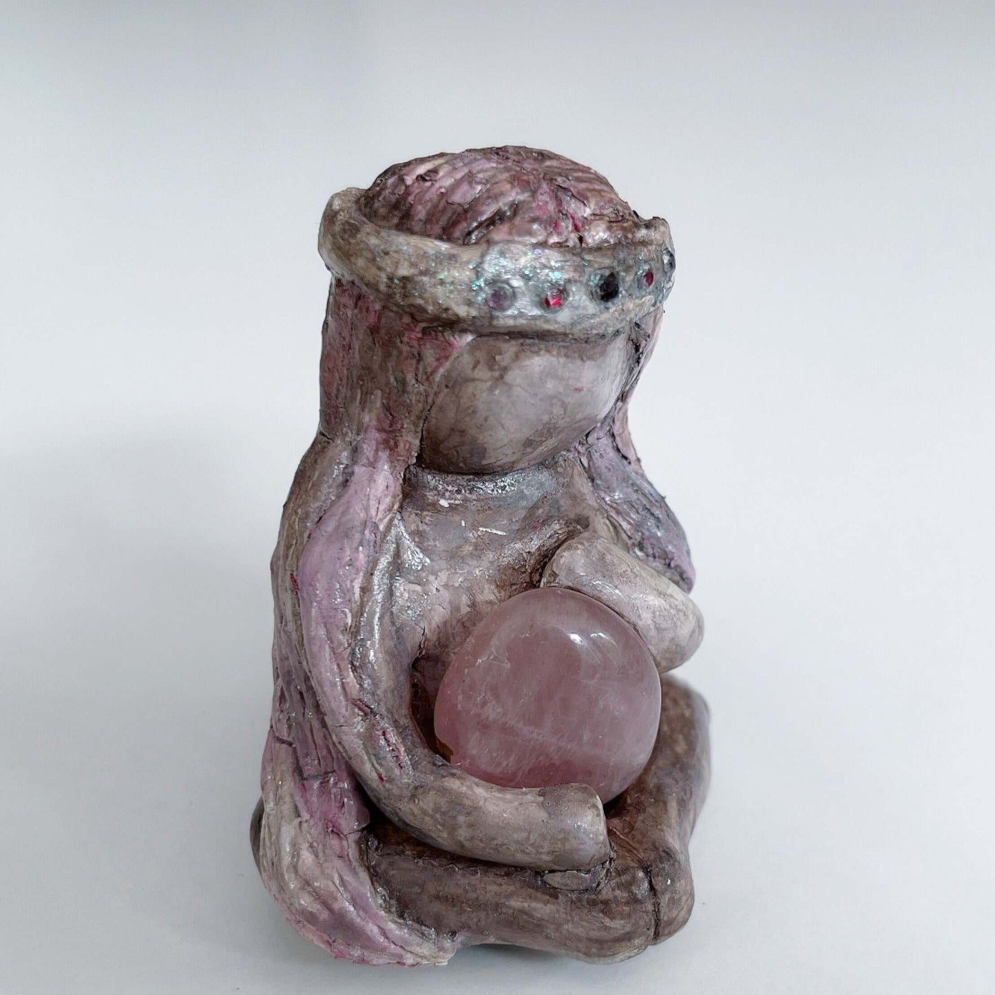 Right view of elemental, brown wash painted figure, jewel band on head, pink wash long hair, holding a tumbled rose quartz.