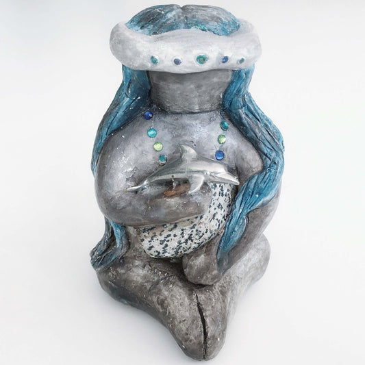 Front of elemental, brown wash painted figure, jewel band on head, bluish long hair, holding a stone and dolphin.