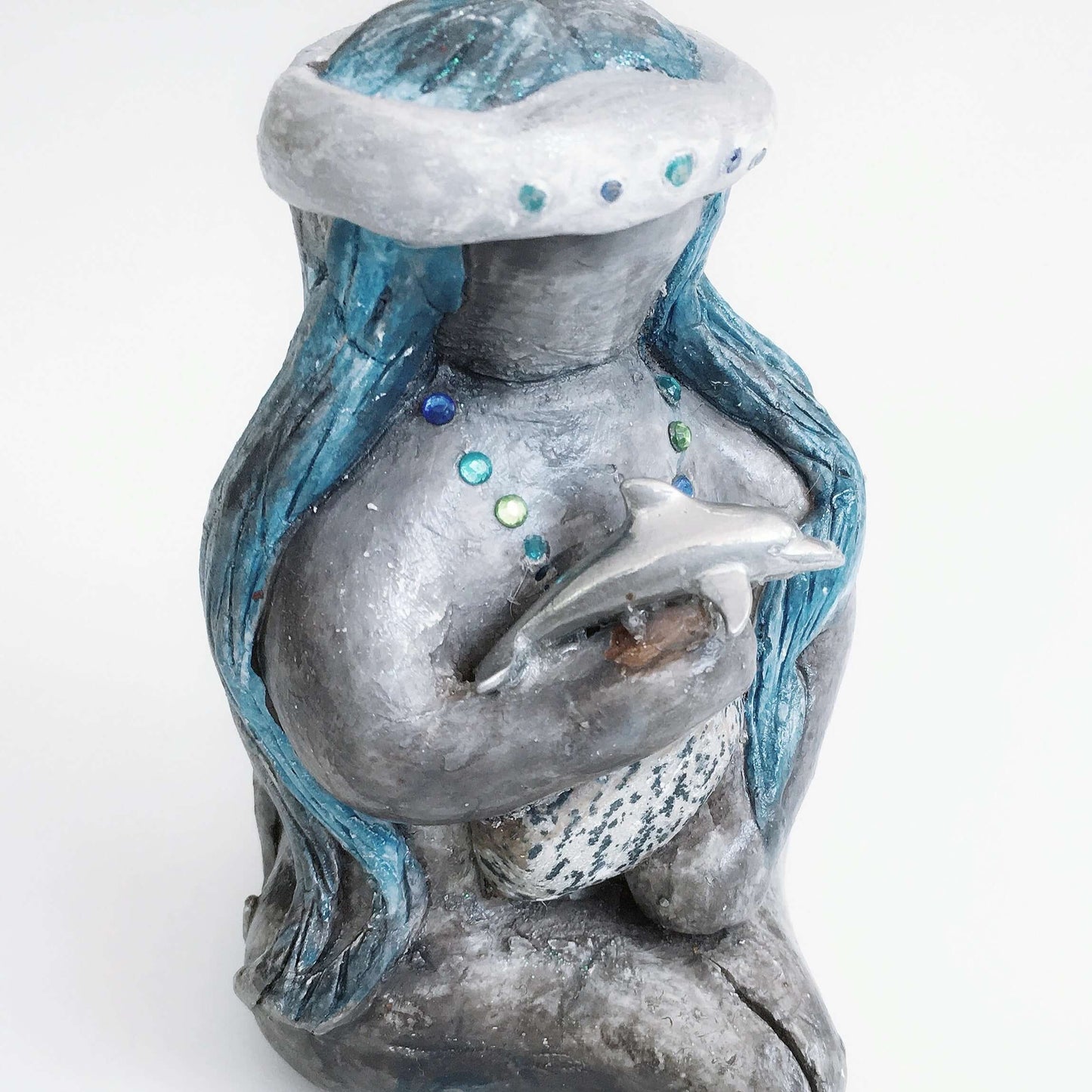 Detail of elemental, brown wash painted figure, jewel band on head, bluish long hair, holding a stone and dolphin.