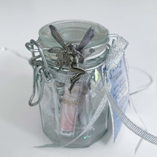 Front view of kilner style jar showing fairy attached to the lid, and ribbon attaching the inscription card.