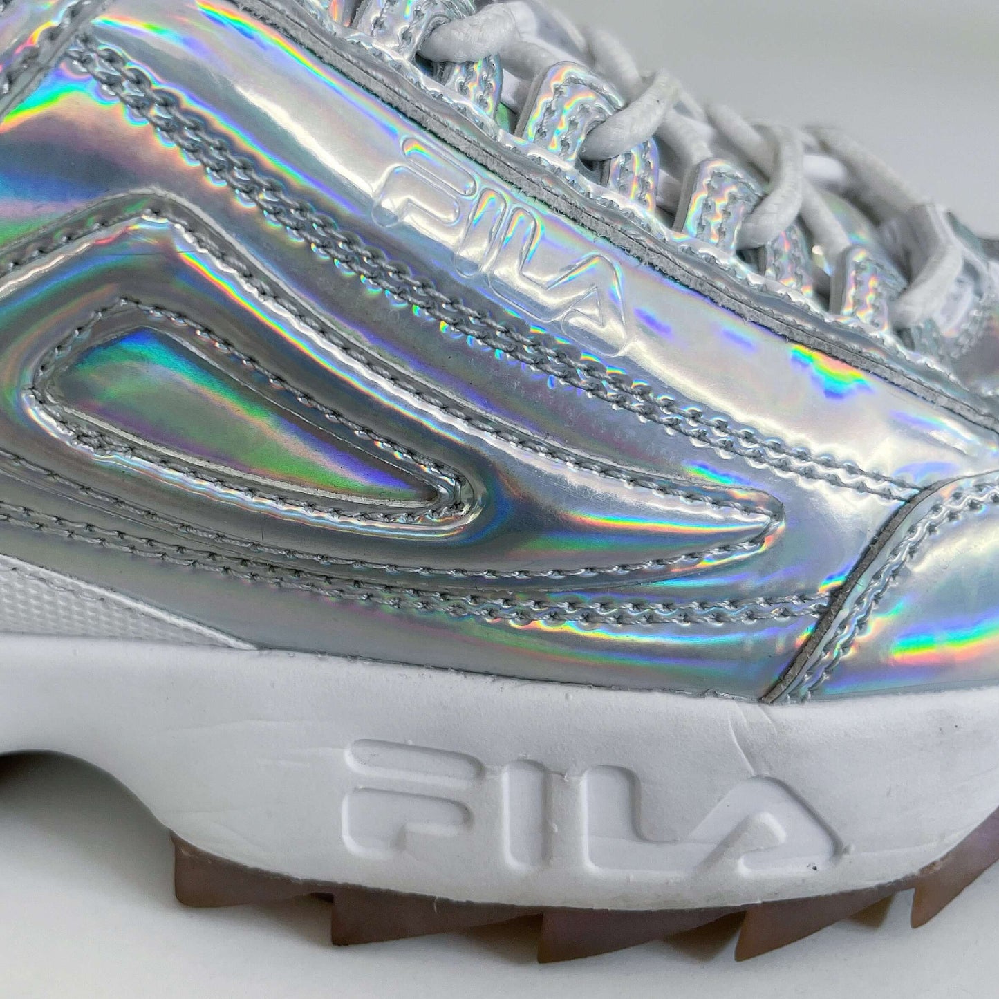 Detail view of shoes showing holographic material and Fila name in the sole.