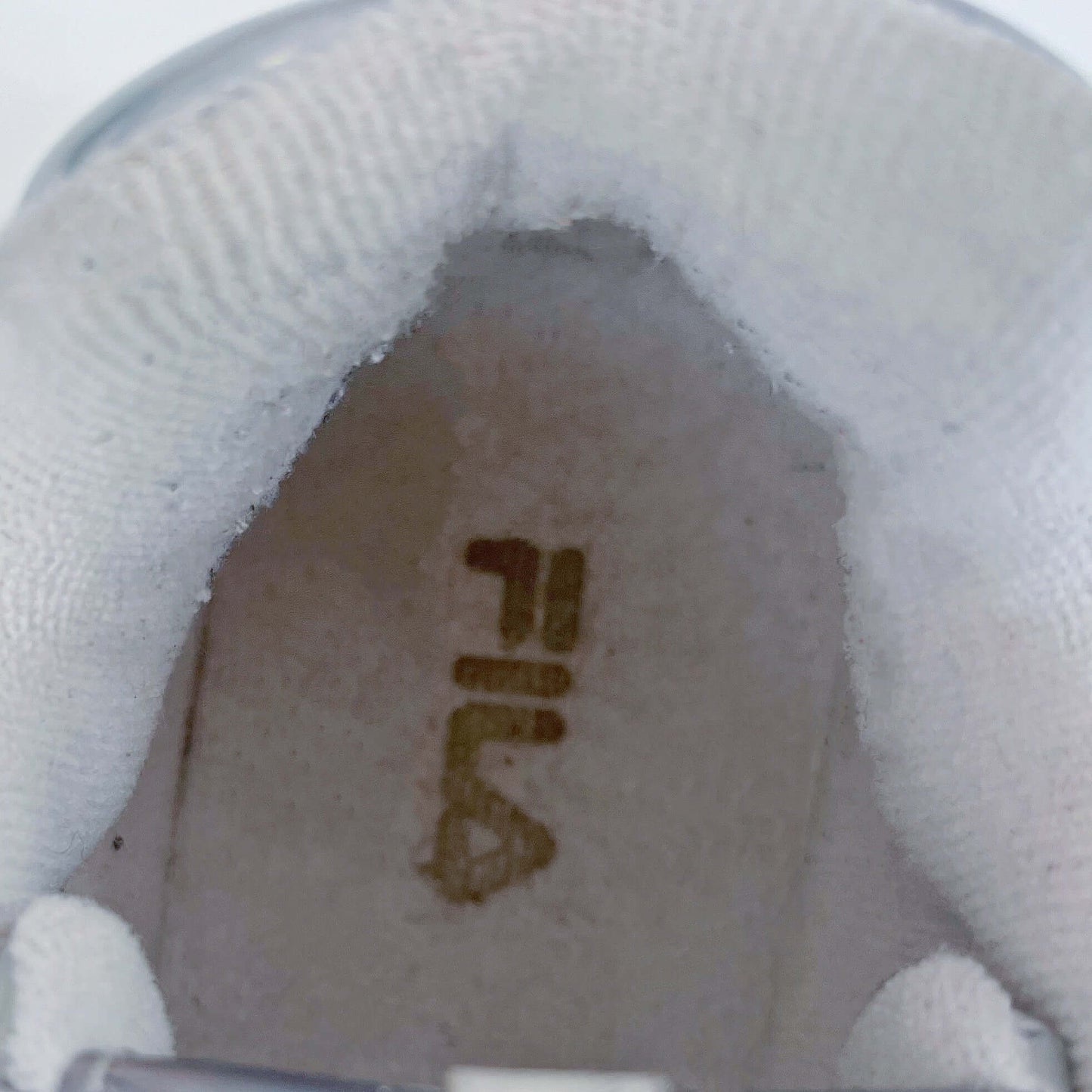 Top detail view of inside the shoe, with gold lettering of the Fila name.