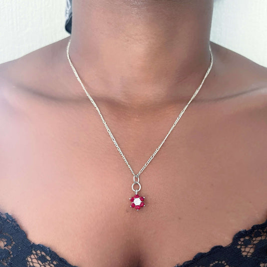 Flower shaped pendant with six garnet petals and a cubic zirconia center, on silver chain