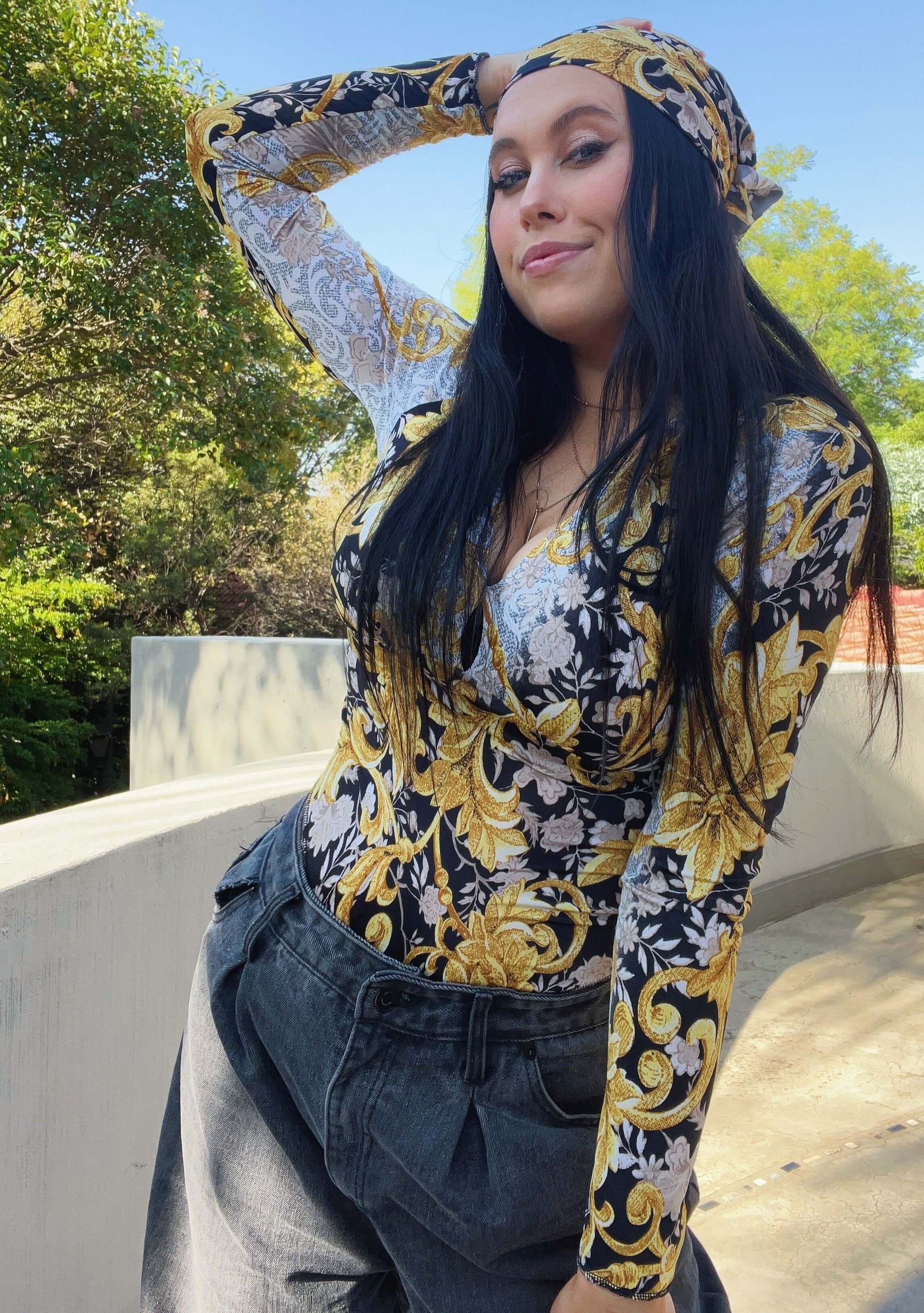 Side view of top, model is standing, wearing a matching fabric bandana, palm trees in the background.