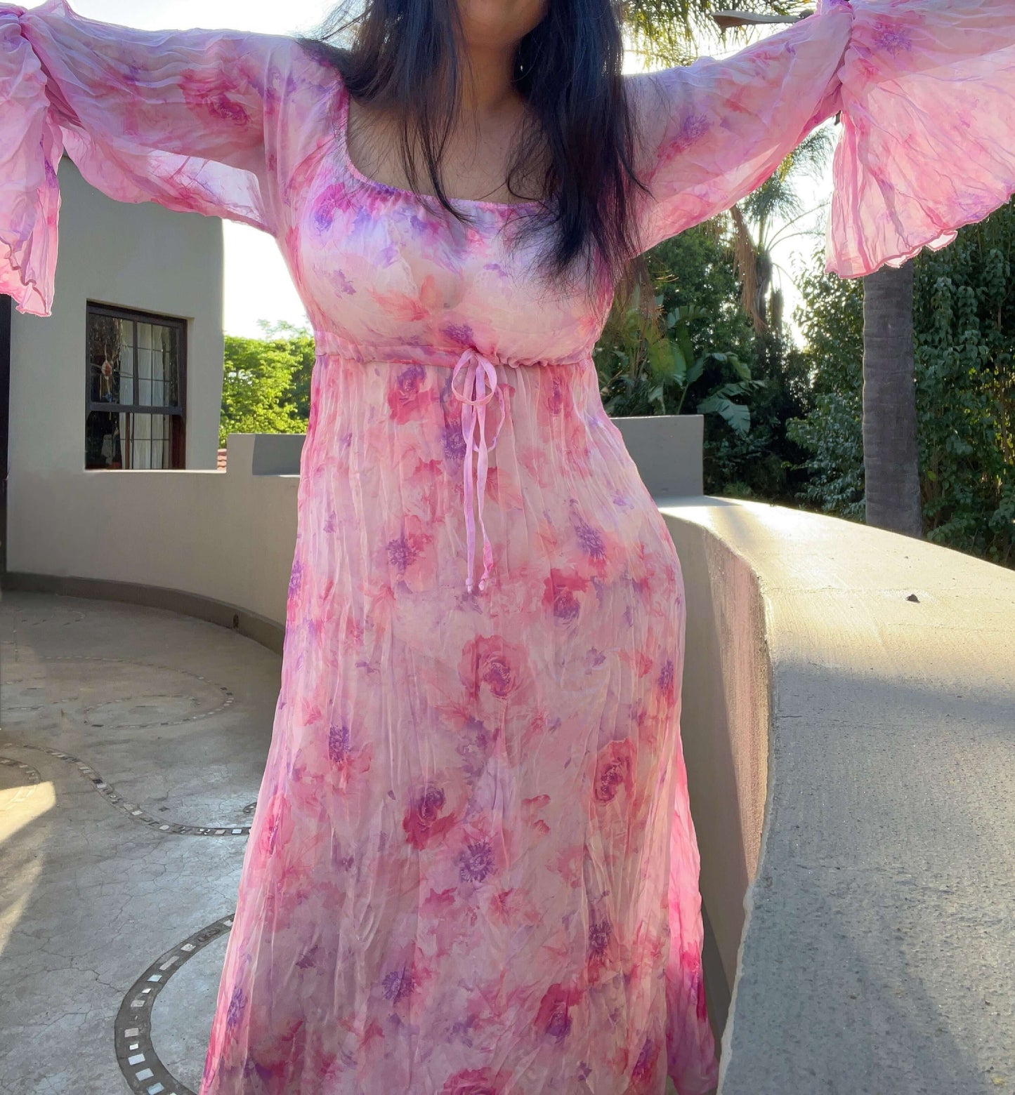 Front view of dress, model's arms outstretched to display the generous frilled sleeve. 