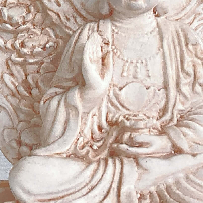 Close up view of buddha, with ornate patterns on his robes.