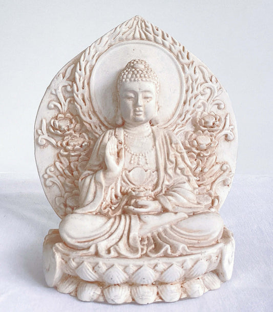 Front view of buddha, ornate patterns on his robes and pedestal, leaning against a halo surrounding the entire statue.