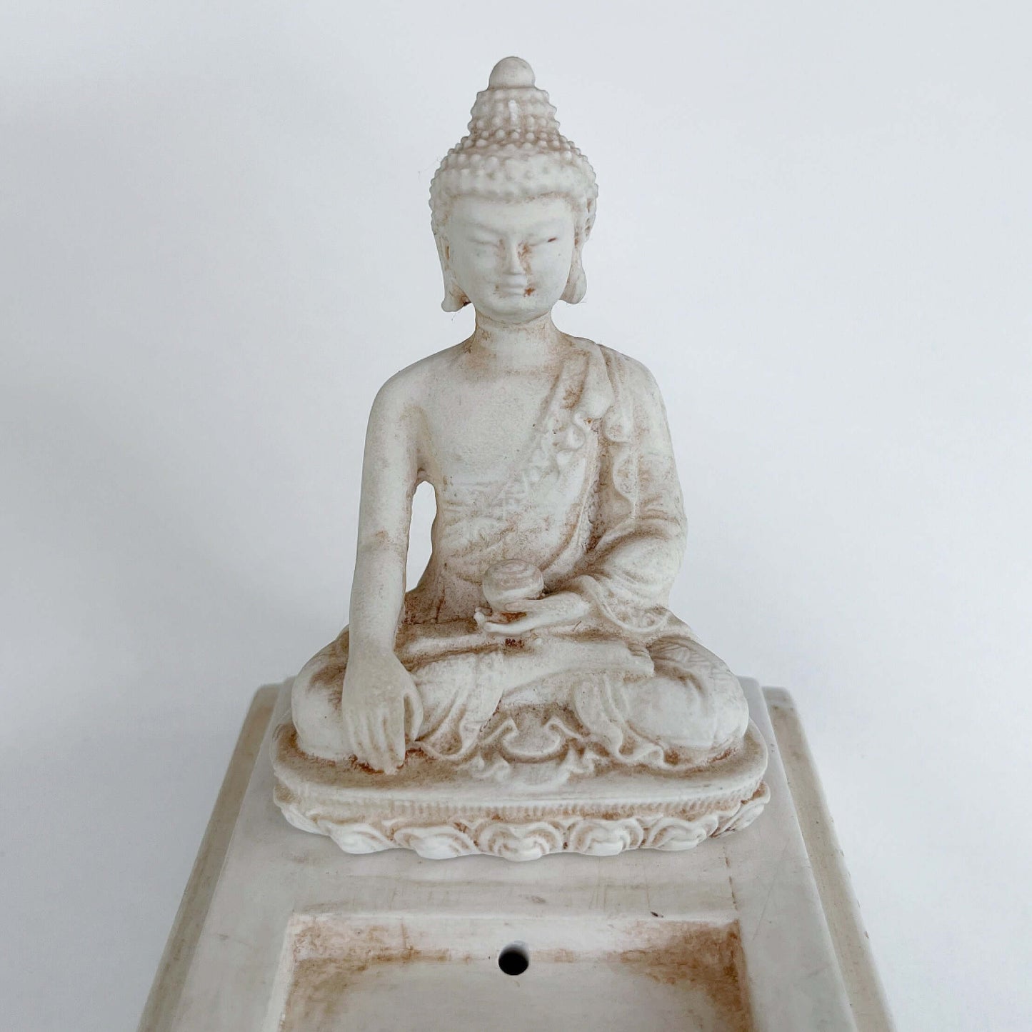 Detail view of the Buddha sitting at one end of long rectangle.