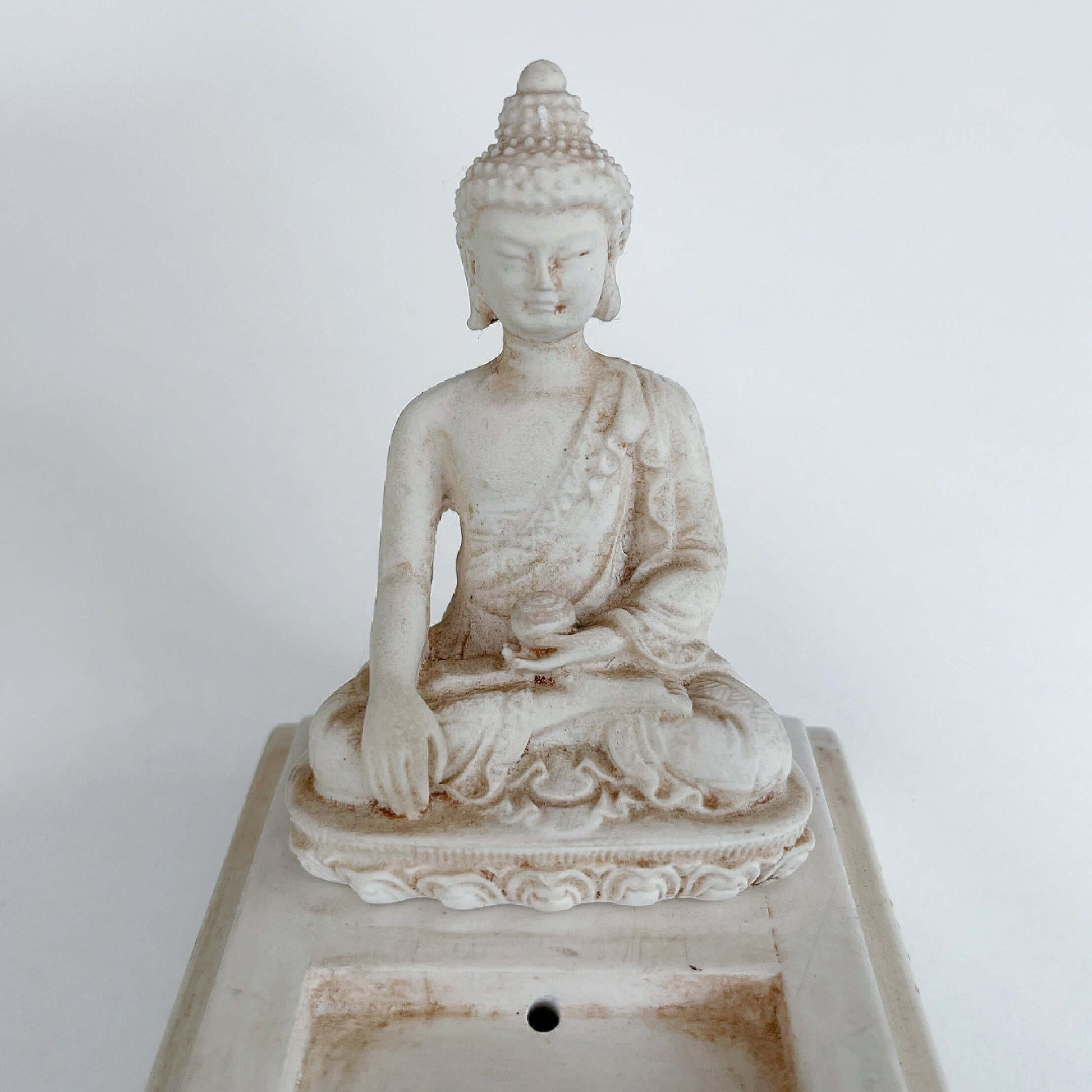 Detail view of the Buddha sitting at one end of long rectangle.