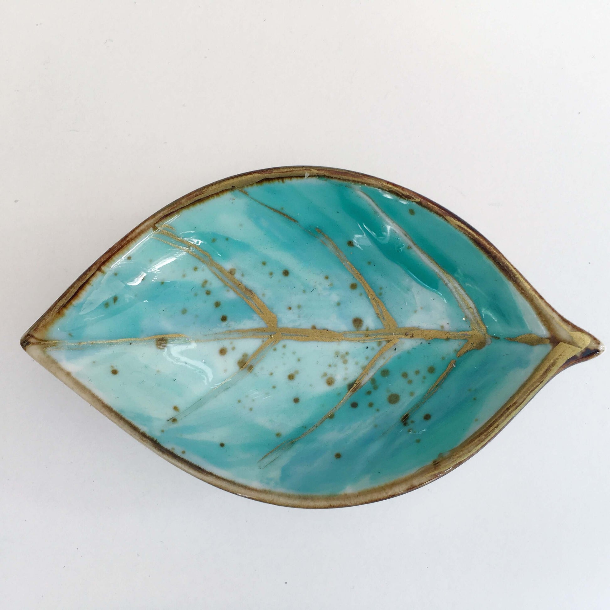 View of turquoise painted ceramic leaf.