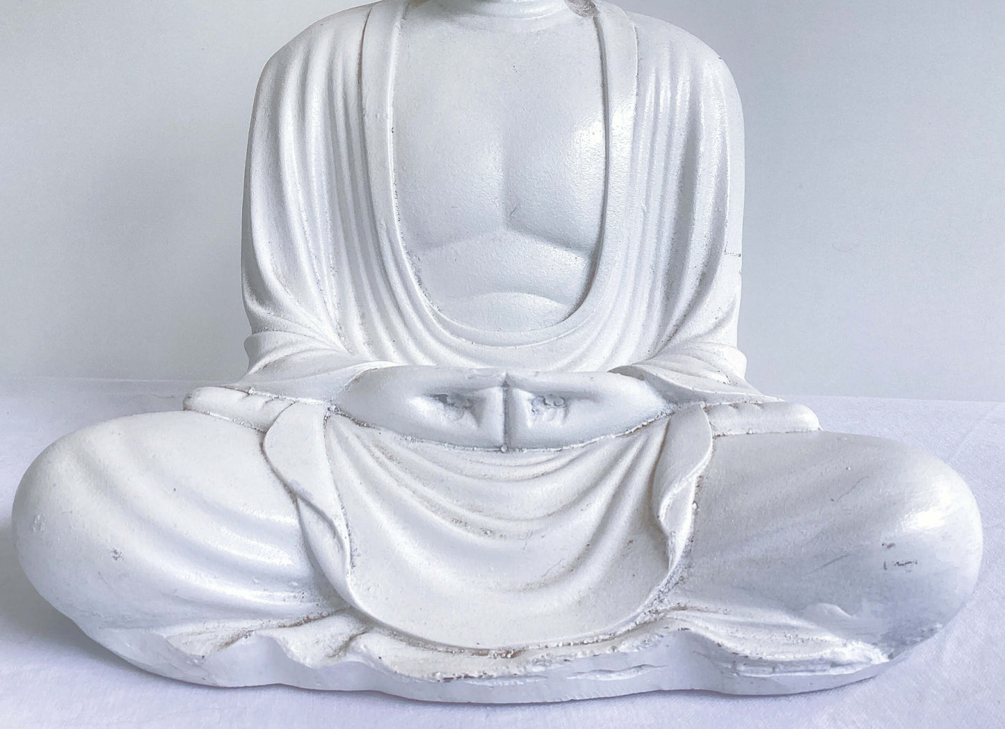 Detail view of white buddha sitting in the lotus position.