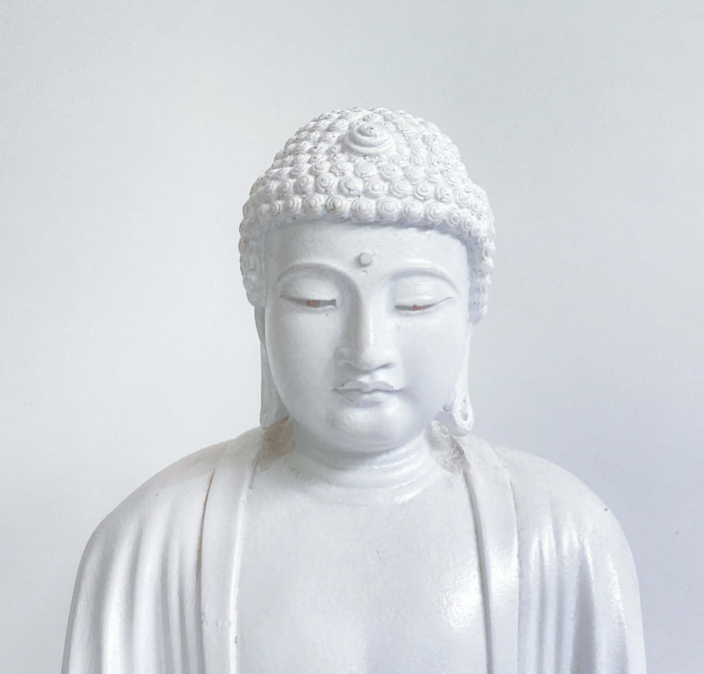Detail view of white buddha head, eyes almost closed looking down.