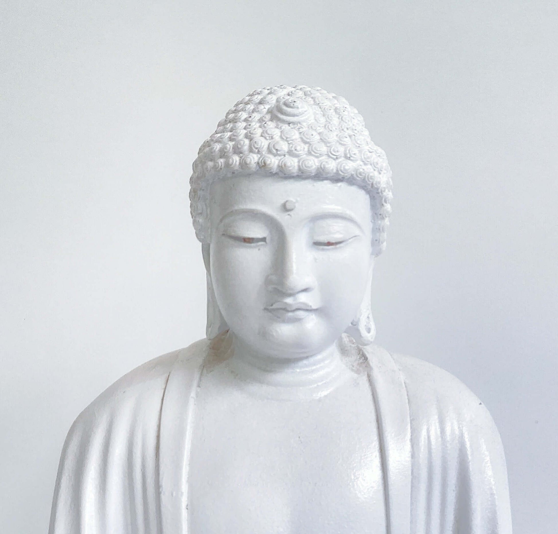 Detail view of white buddha head, eyes almost closed looking down.