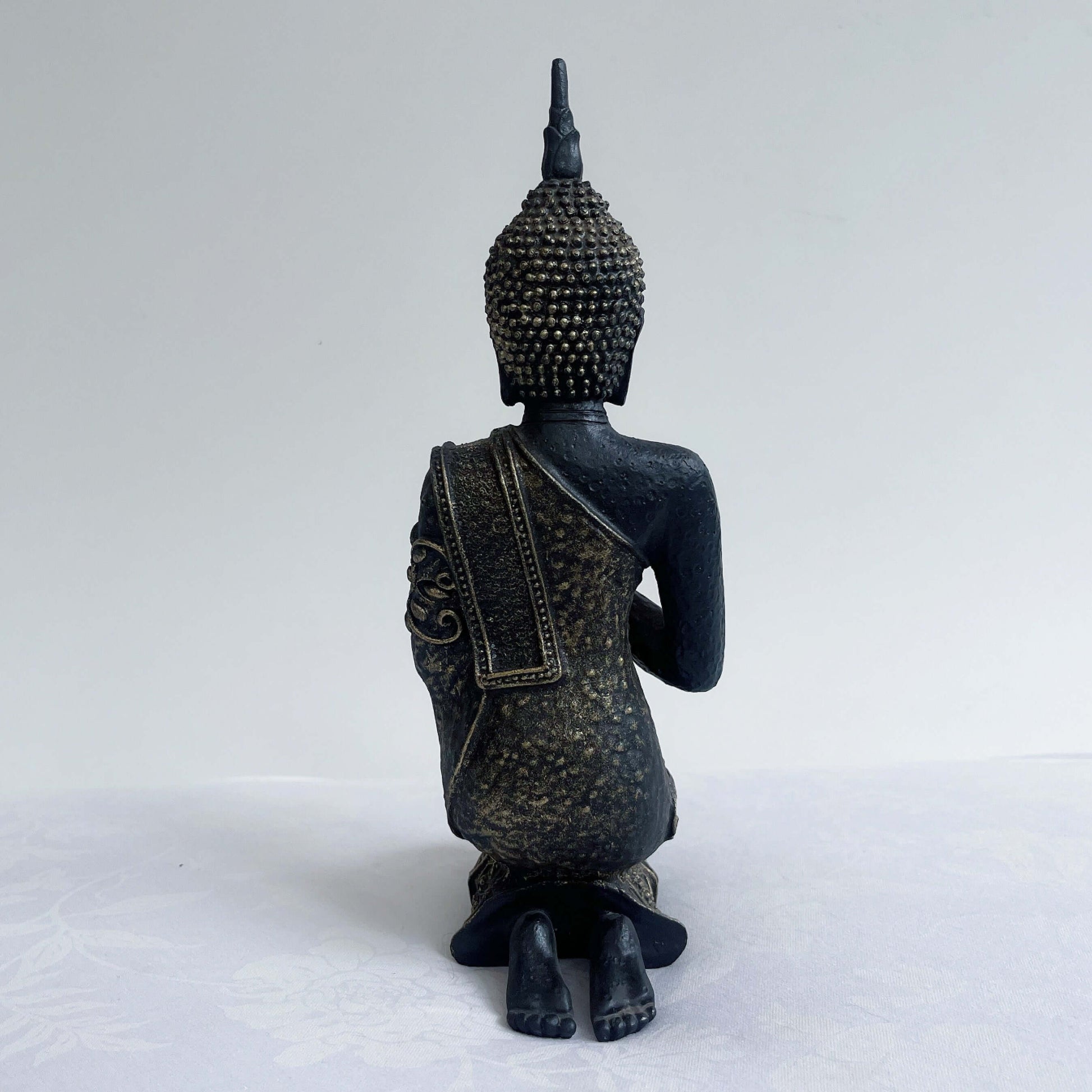 Back view of buddha kneeling, with ornate robes and detailing, ushnisha on head, washed black and silver painting