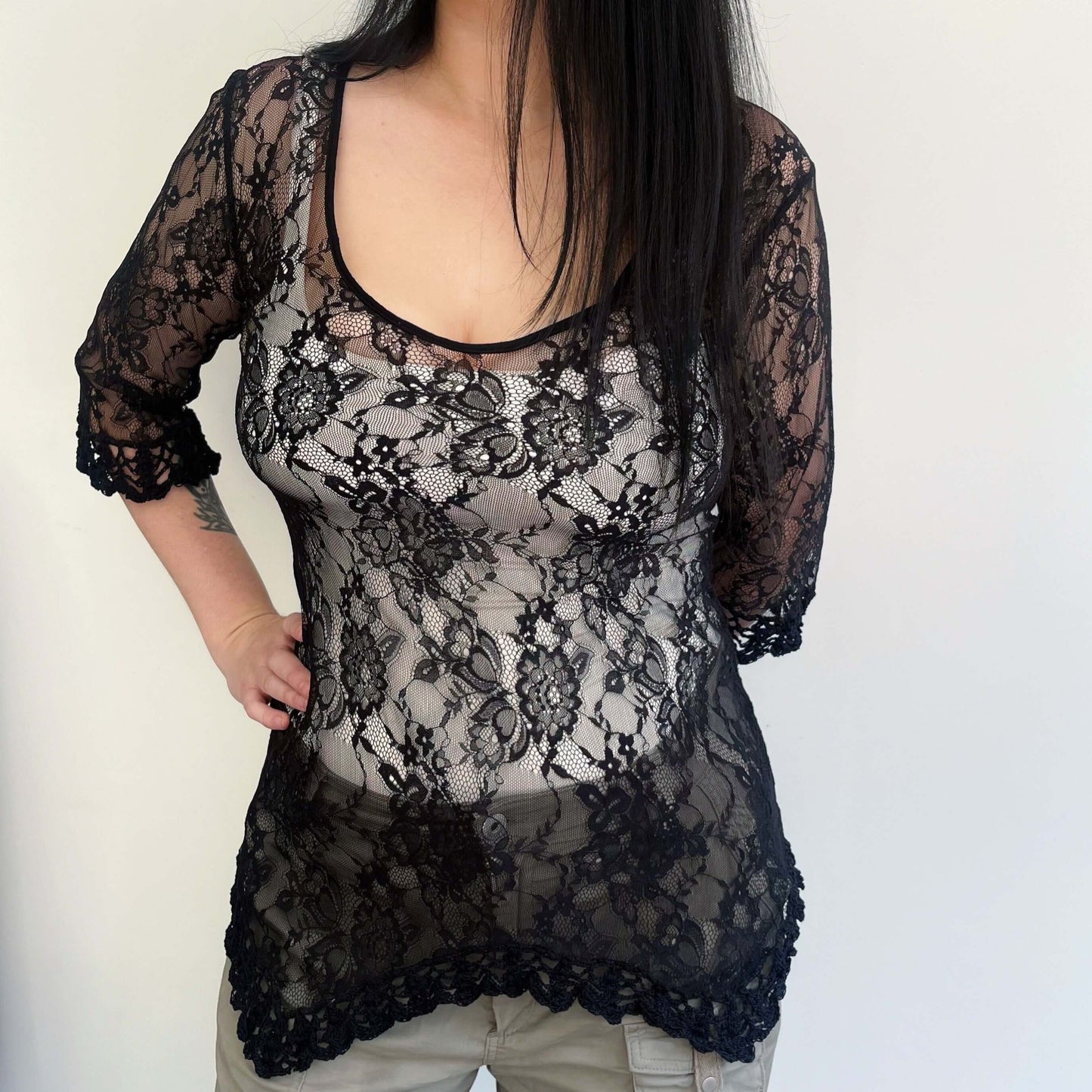 Front view of black lace three quarter sleeve tunic, with black crochet on the jagged hem, and edge of sleeve. 