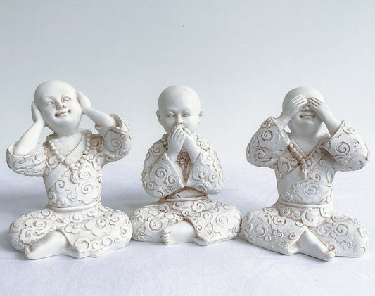 Front view of monks, all three in a row, natural off white colors, with ornate robes.