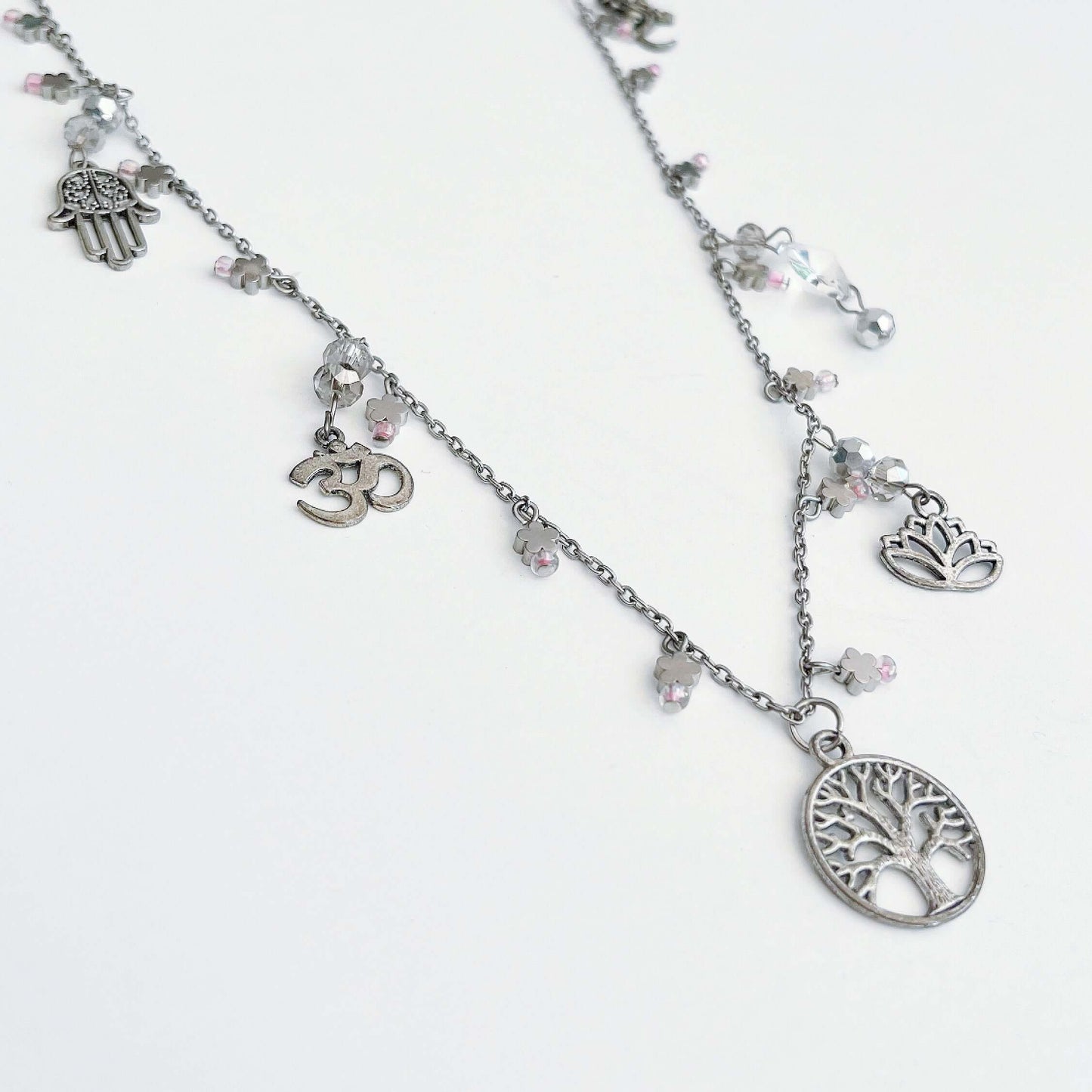 Side view of charm necklace, tree of life at the center front, with charms and beads added elsewhere.