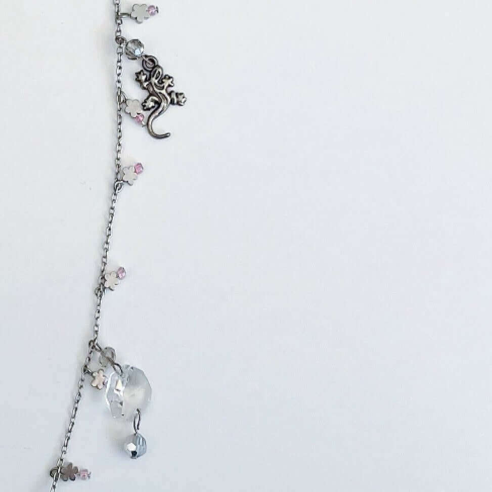 Detail view of charm necklace, showing lotus flower and gecko